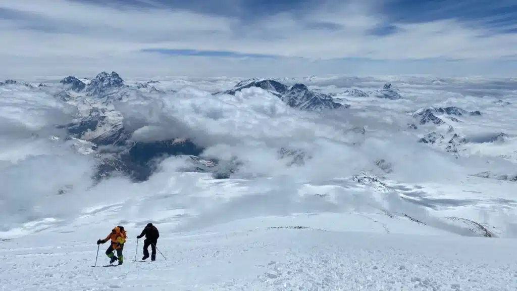 Climbers ascend Elbrus, surrounded by clouds and stunning peaks - B4Experience.
