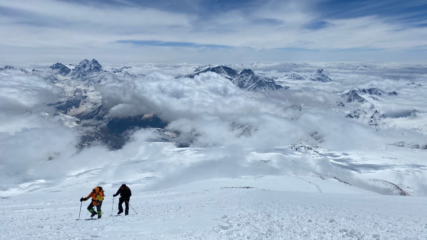 Climbers ascend Elbrus, surrounded by clouds and stunning peaks - B4Experience.