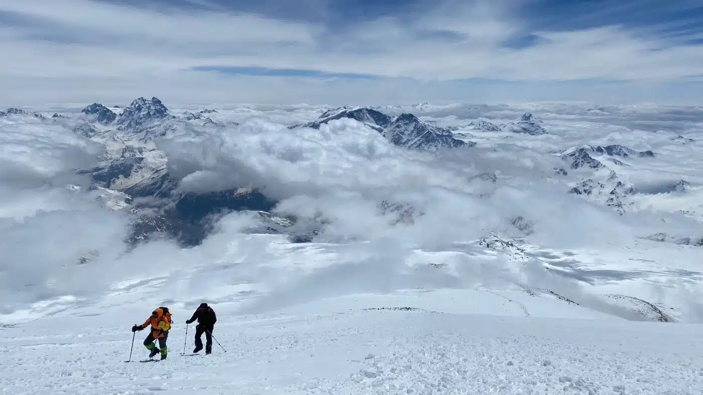 Climbers ascend Elbrus, surrounded by clouds and stunning peaks - B4Experience.