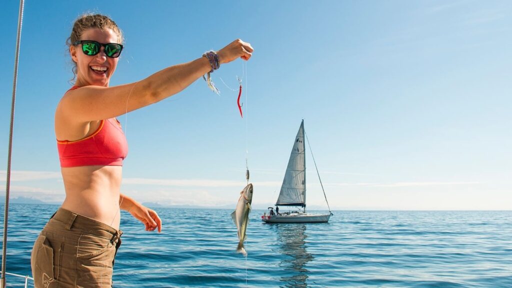 Woman smiles while showing her cod caught in the sea