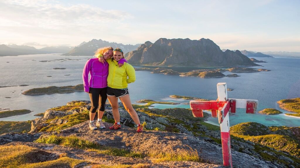 Girls hugging and smiling with fjord landscape