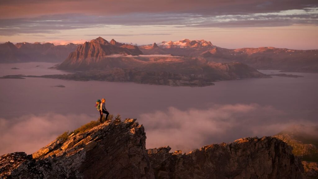 Woman hiker on top of mountain, wonderful view of fjord