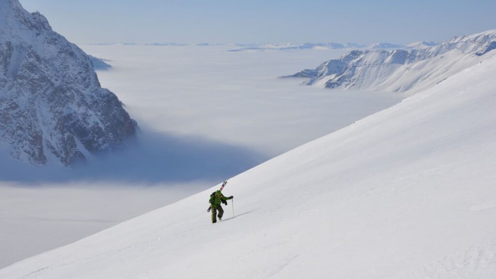 Skier climbing the mountain, white and frozen landscape