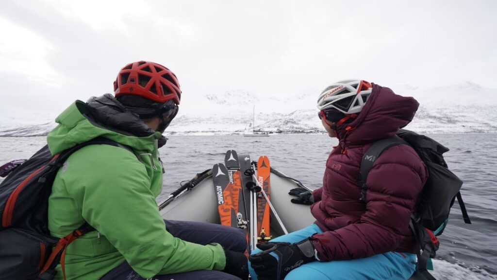 Two skiers riding a zodiac head towards the sailboat