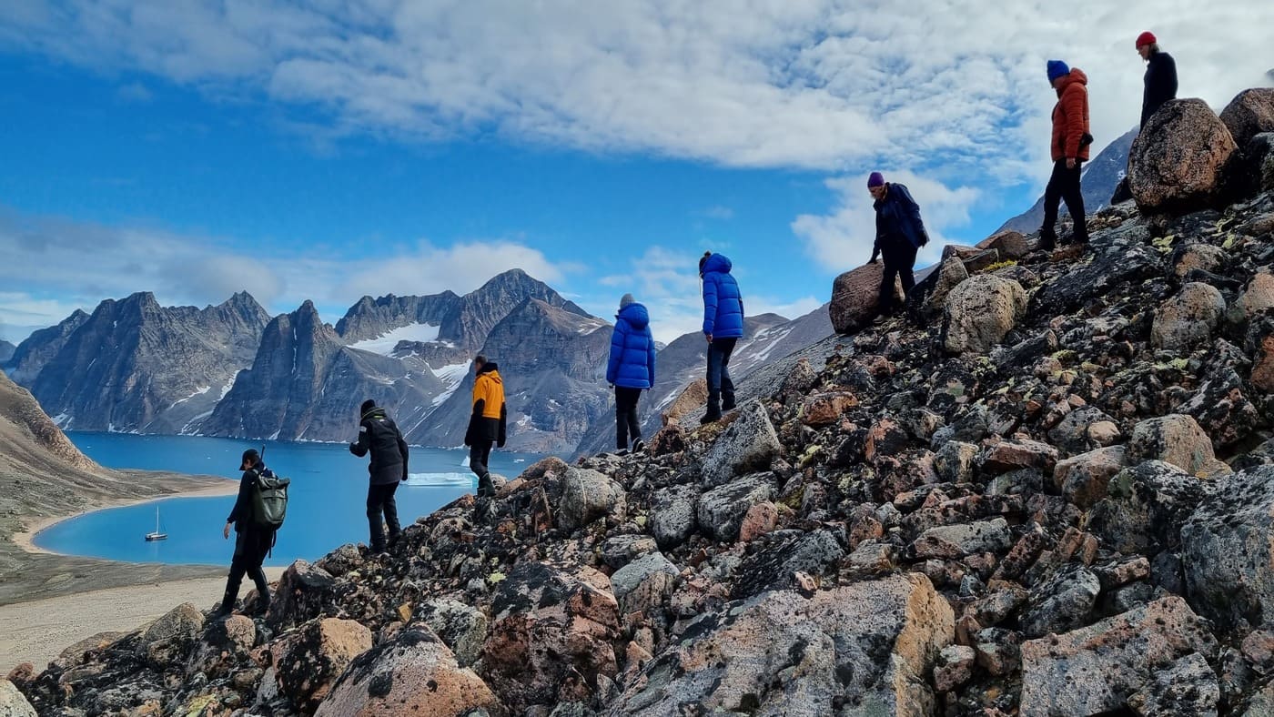 People taking a short walk along the coast of Greenland.