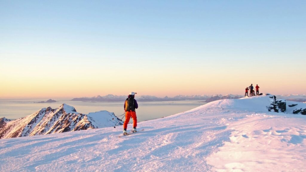 Skiers on top of a mountain in Lofoten