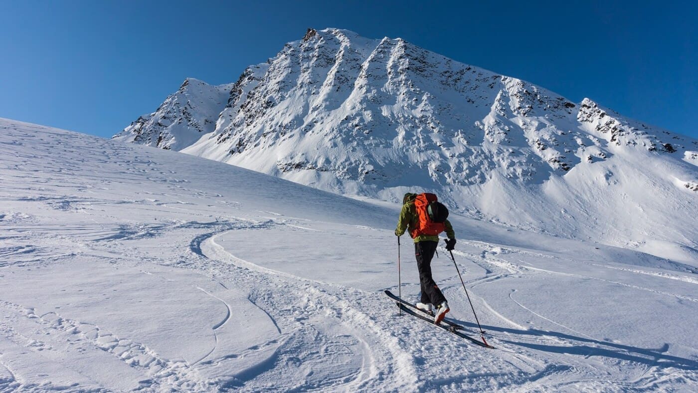 Skier going up the mountain with his skis to achieve a good descent