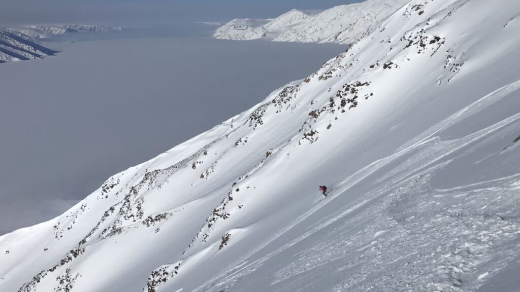 Skier sliding a large slope towards the sea