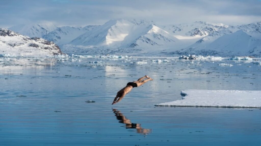 Man jumping into the sea in a frozen fjord in Norway