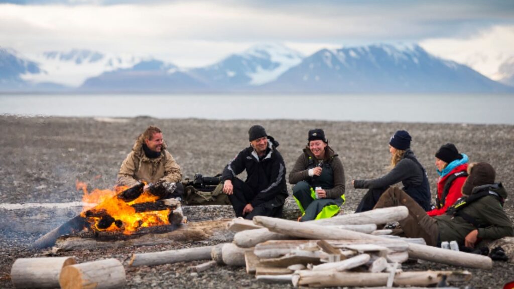 Group of people enjoying a bonfire dinner on a beach in Svalbard