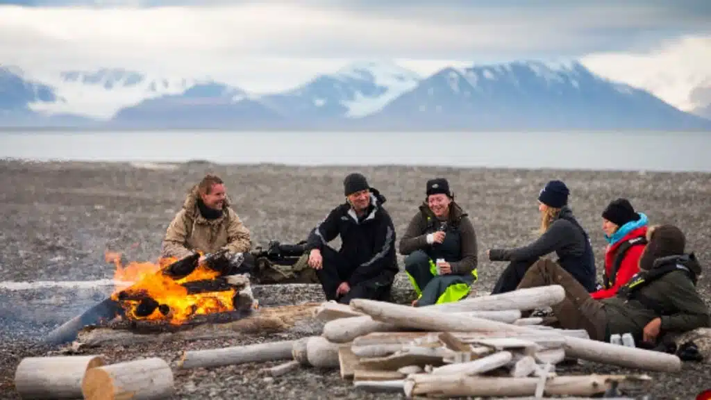 Group of people enjoying a bonfire dinner on a beach in Svalbard
