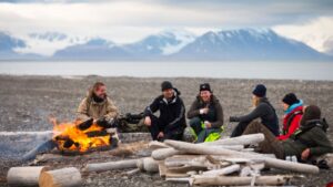 Group of people enjoying a bonfire dinner on a beach in Svalbard