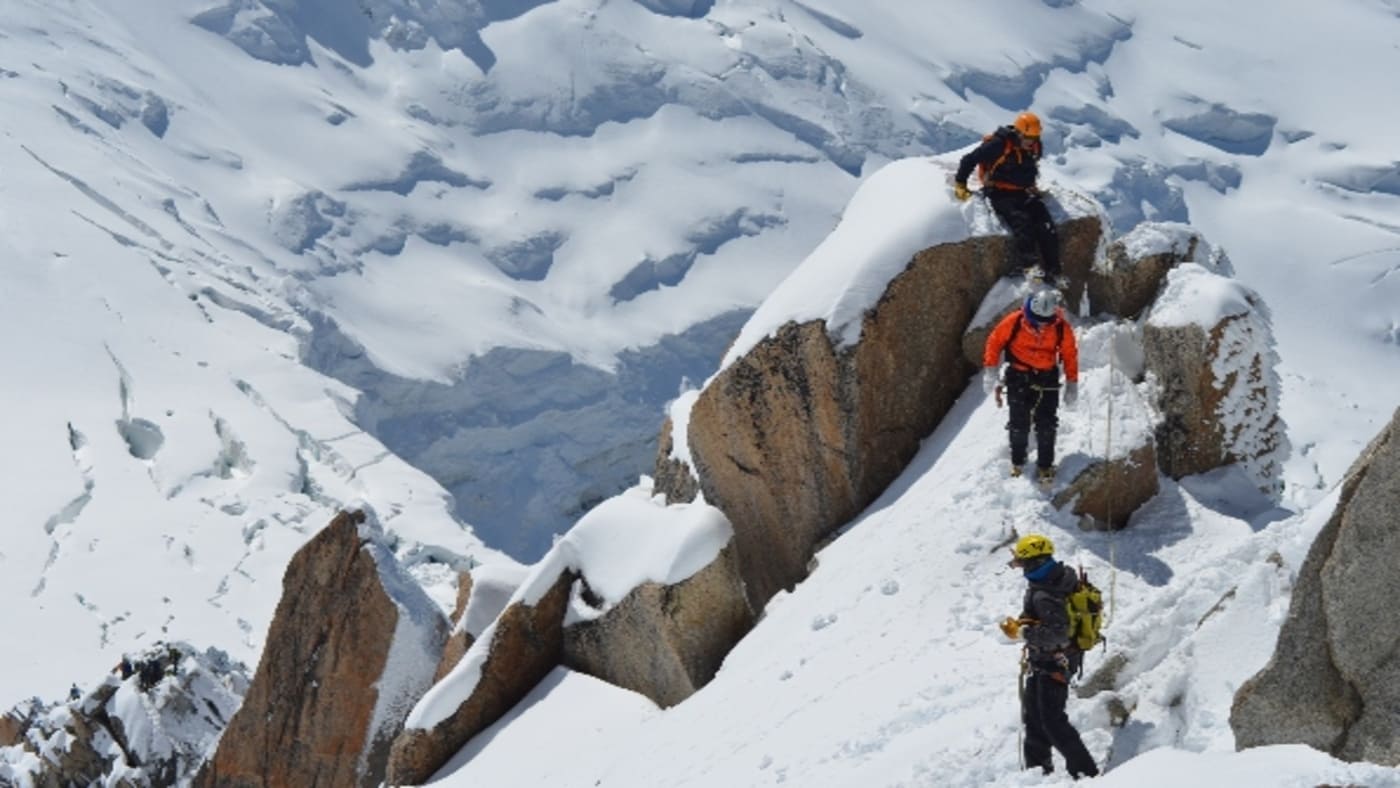 Alpine technical improvement-climbers navigating a steep, snowy ridge with ropes and gear - B4Experience