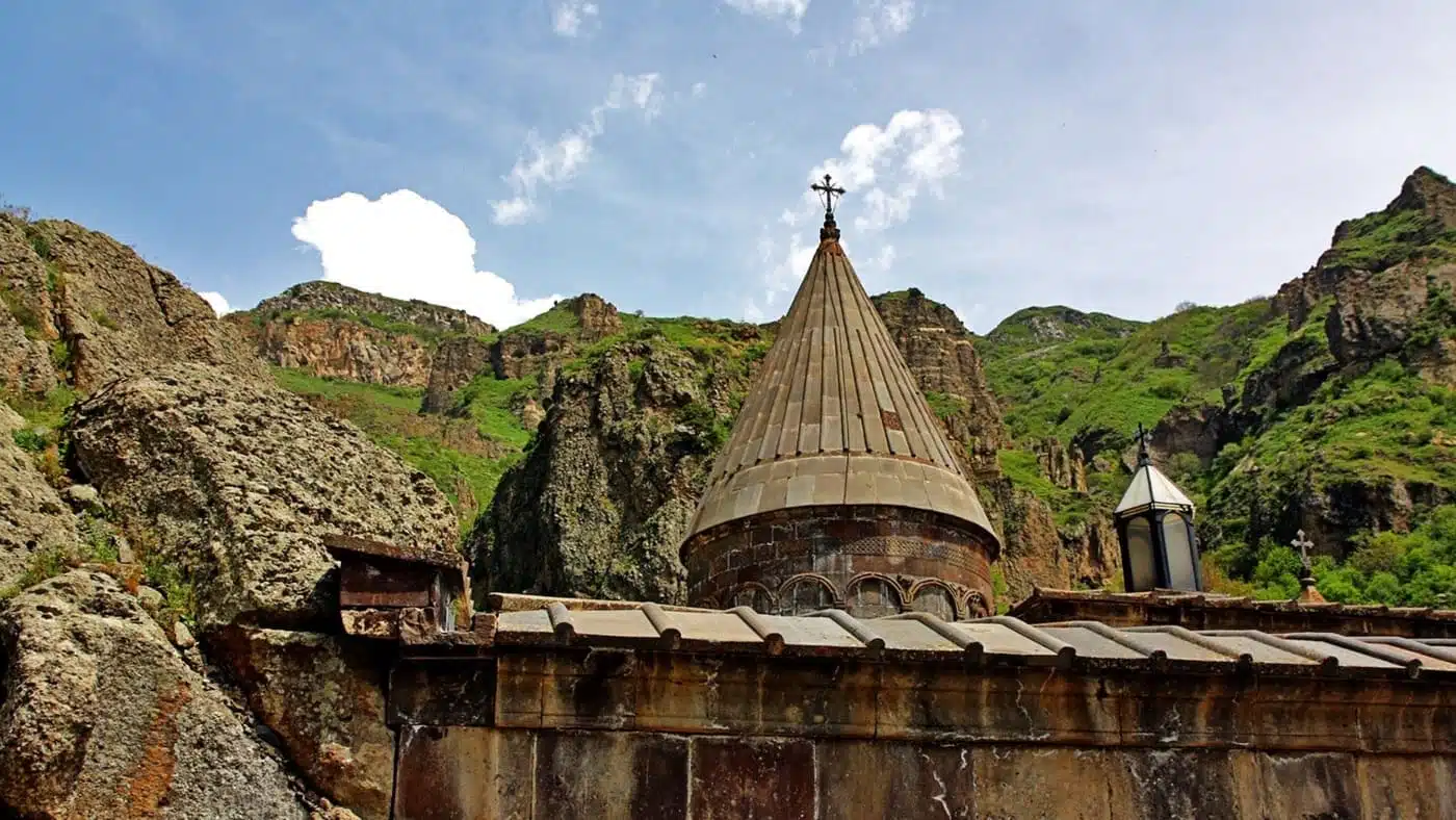 Ancient Armenian monastery set against lush mountain cliffs with B4Experience