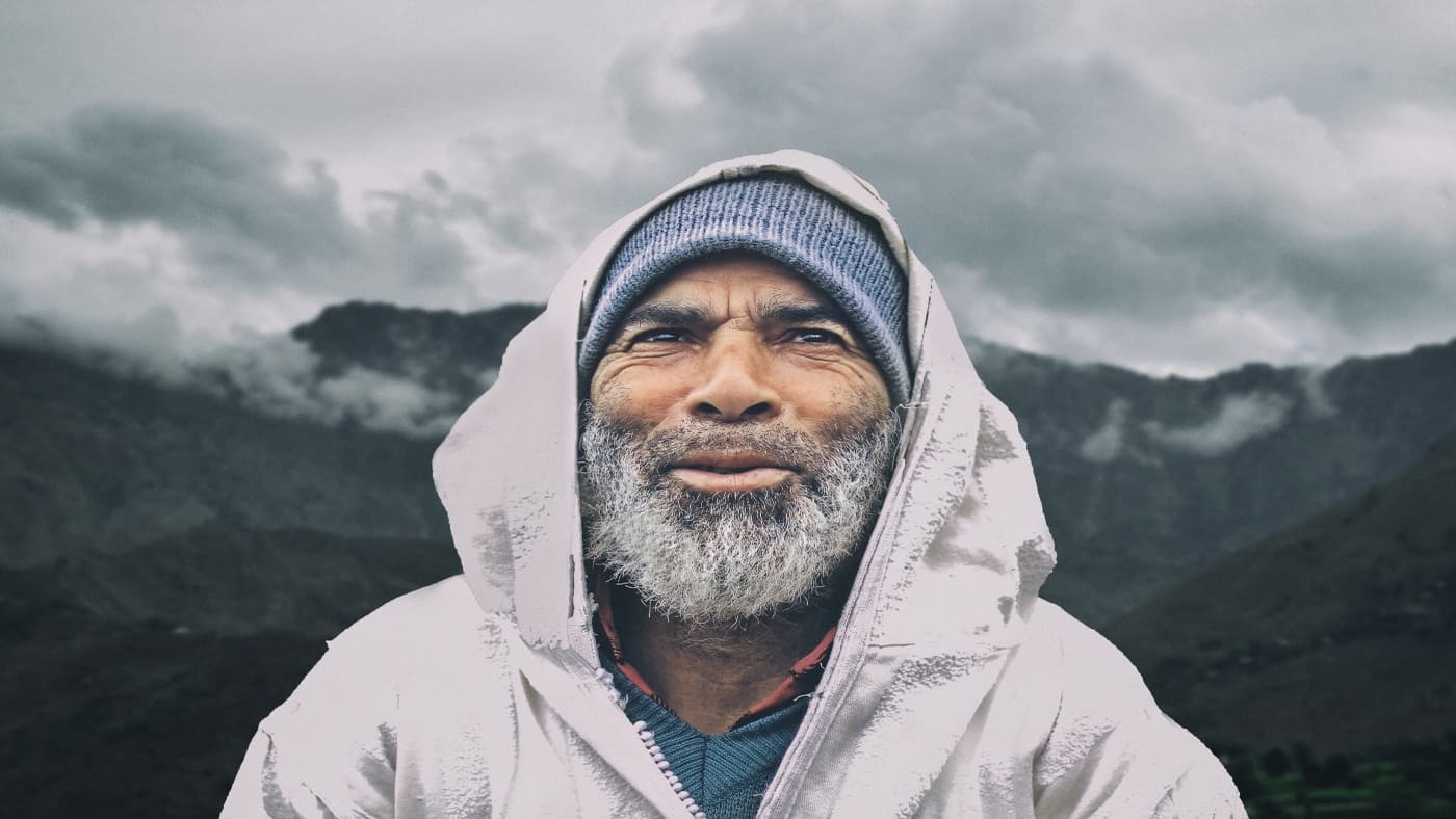 Bearded man in a hooded jacket, mountains in the background with B4Experience