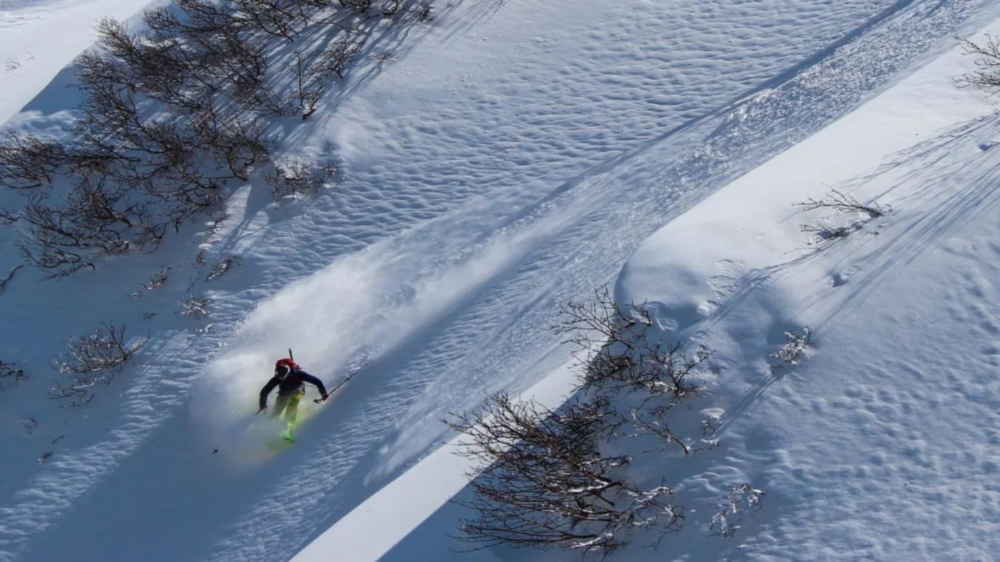 Skier carving through deep powder on a snowy slopes with B4Experience