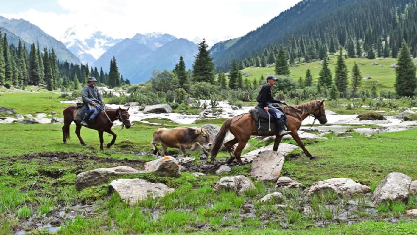 Horseback riders in a scenic Kyrgyzstan valley with B4Experience