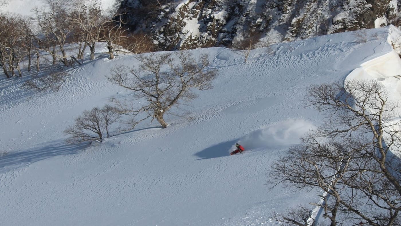 Skier gliding through deep powder in a snowy landscape with B4Experience