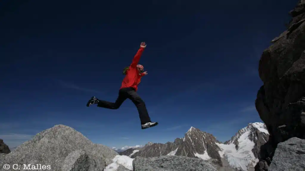 Jordi Tosas leaping over rugged mountain terrain under a clear blue sky in Mont Blanc with B4Experience