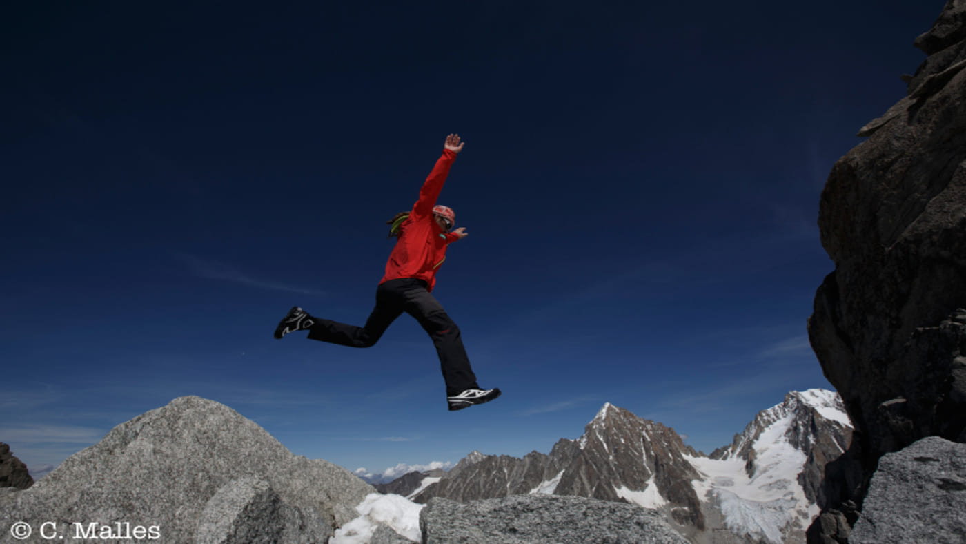 Jordi Tosas leaping over rugged mountain terrain under a clear blue sky in Mont Blanc with B4Experience