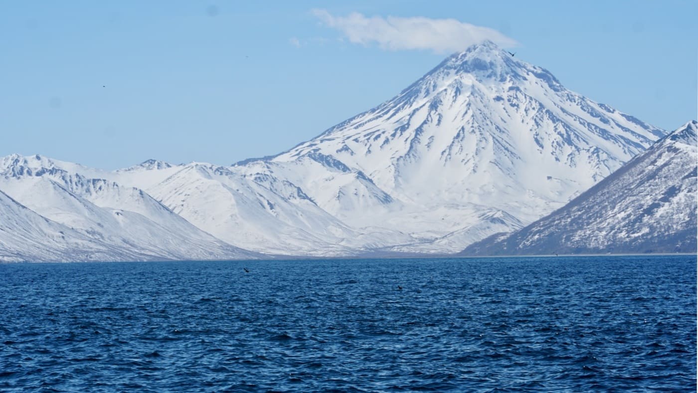 Snow-covered volcano rising over the blue waters of Kamchatka with B4Experience