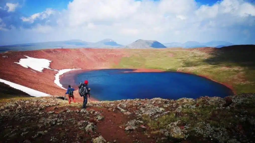 Lake Akna in Armenia, hikers approach a stunning crater lake by colorful volcanic terrain - B4Experience