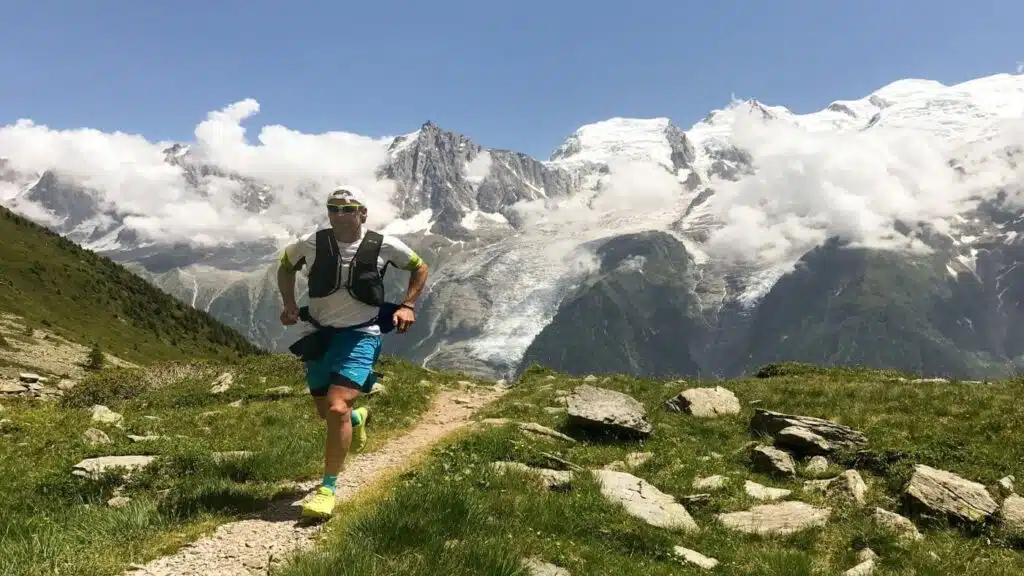 Trail runner on a mountain path with Mont Blanc behind.