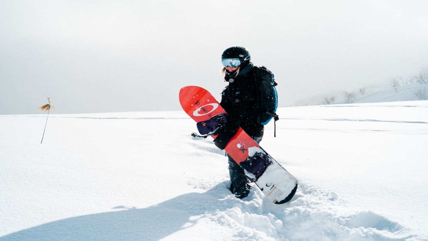 Snowboarder walking through deep snow in a white landsape in Japow with B4Experience