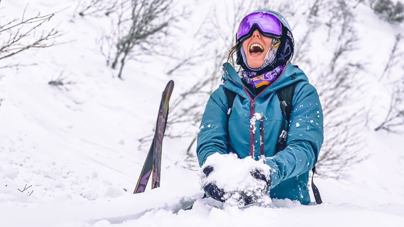 Smiling skier enjoying deep powder in a snowy forest with B4Experience