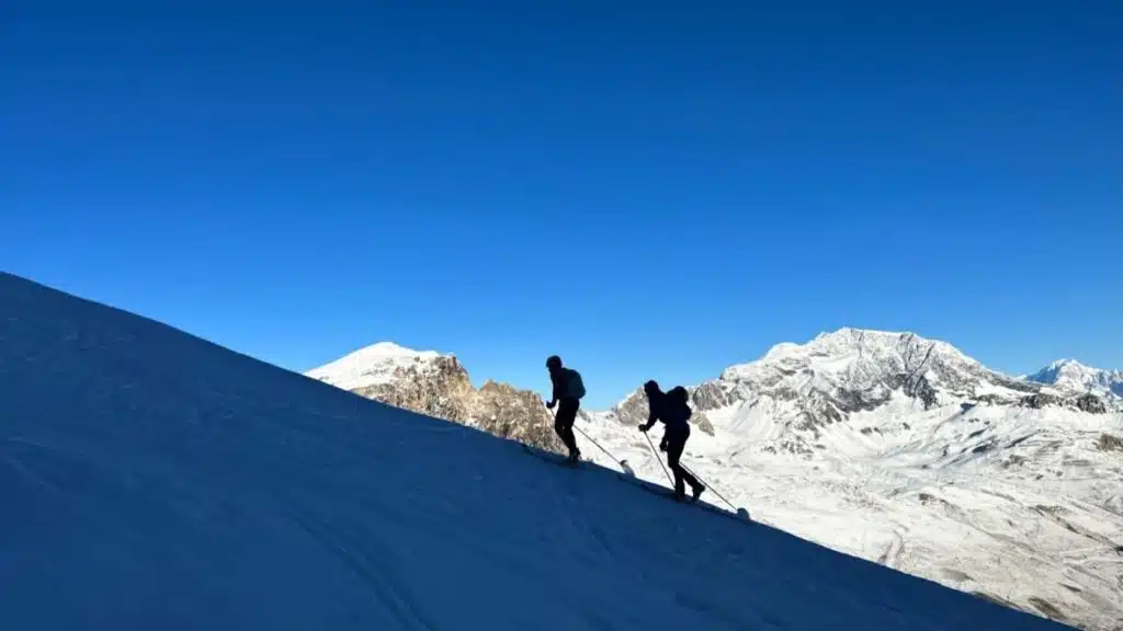 Skiers ascending a snowy ridge in the Alps with B4Experience