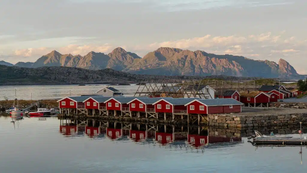 Red lodges on the water in Lofoten, with mountains behind.