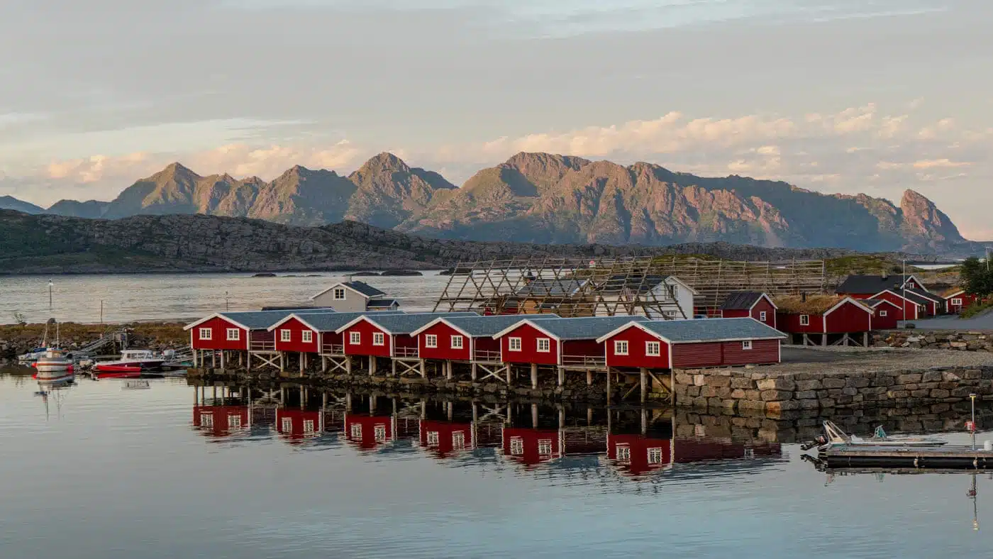 Red lodges on the water in Lofoten, with mountains behind.