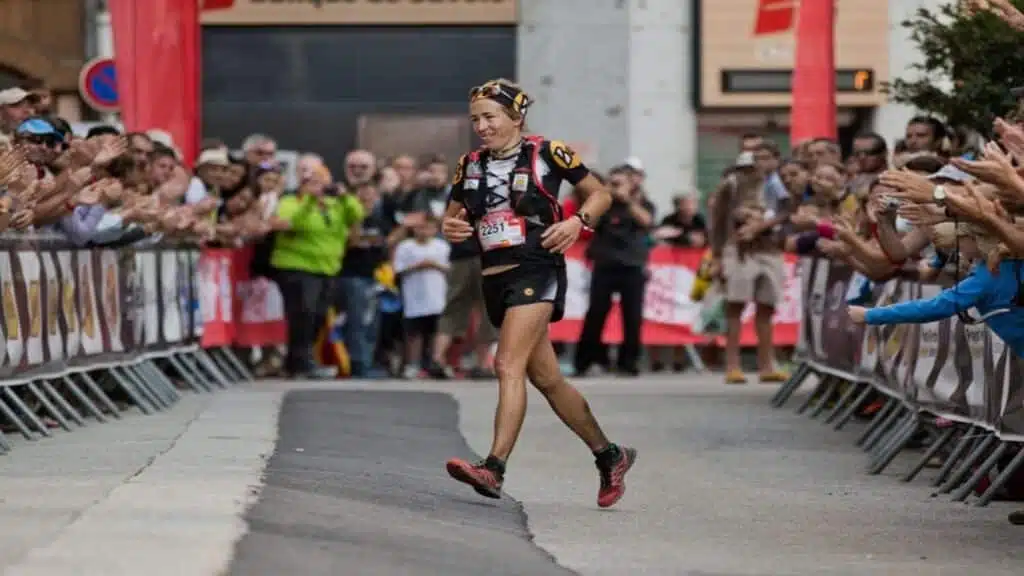 Trail runner finihing a race, cheered by a crowd - B4Experience.
