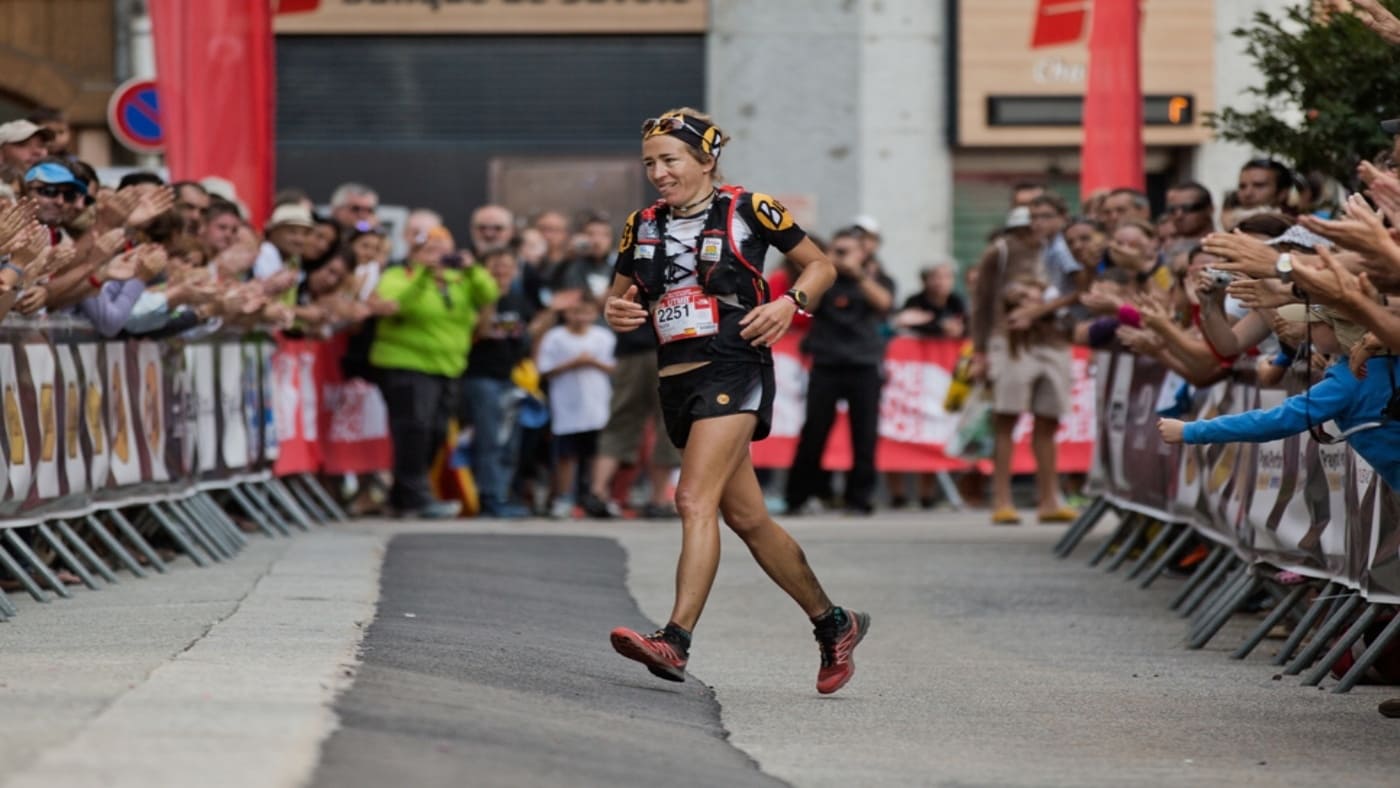 Trail runner finihing a race, cheered by a crowd - B4Experience.