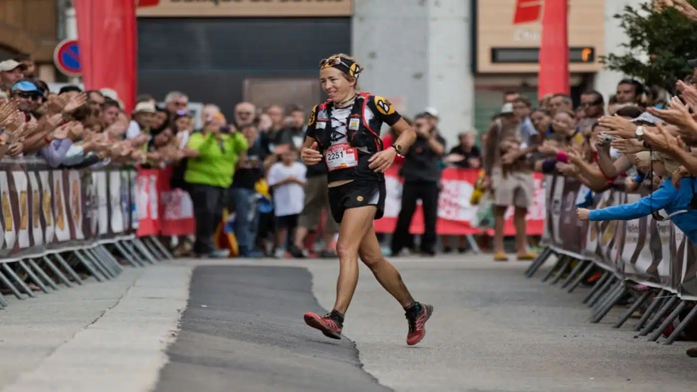 Trail runner finihing a race, cheered by a crowd - B4Experience.