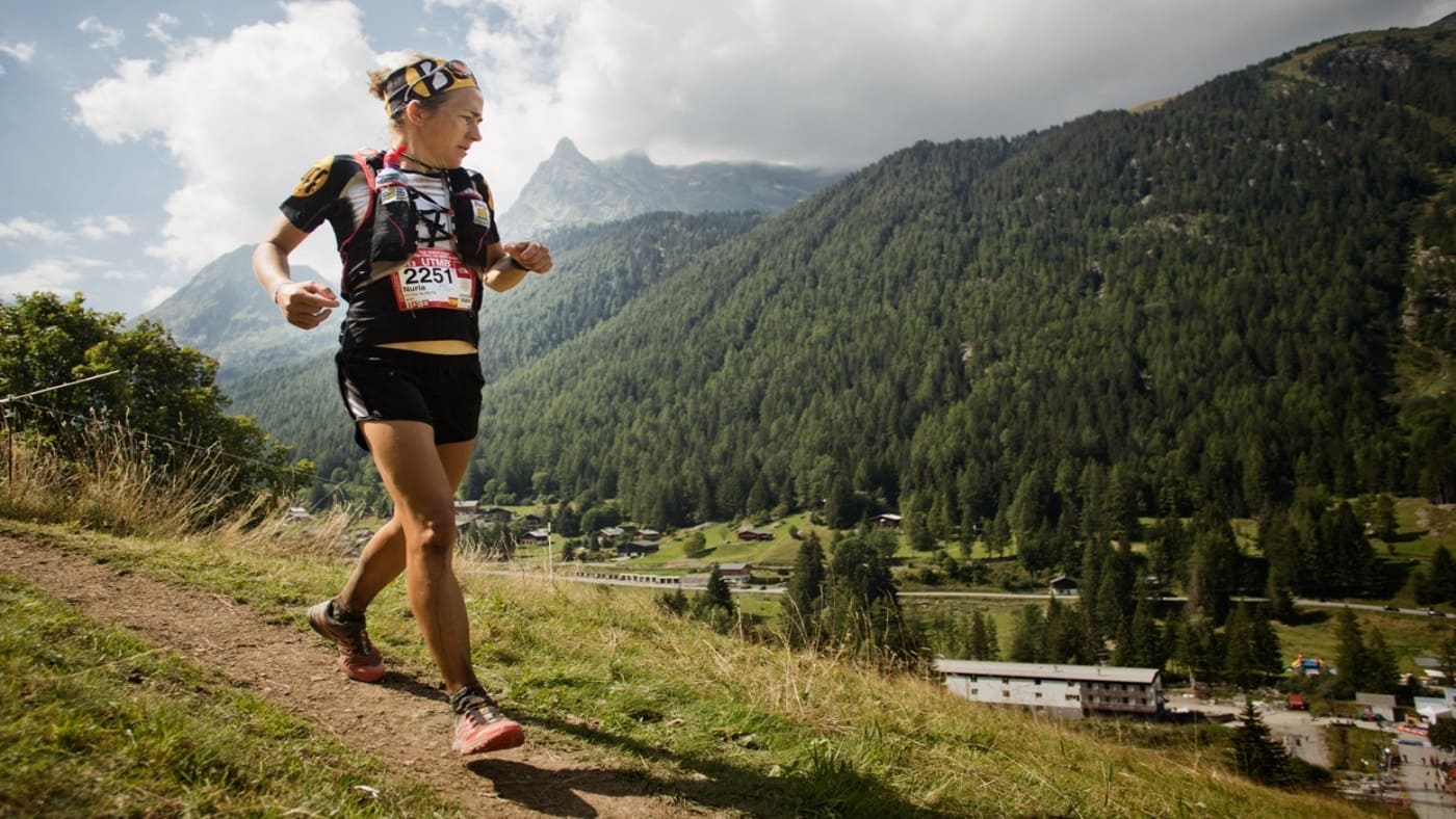 Trail runner on a mountain path overlooking a valley - B4Experience.