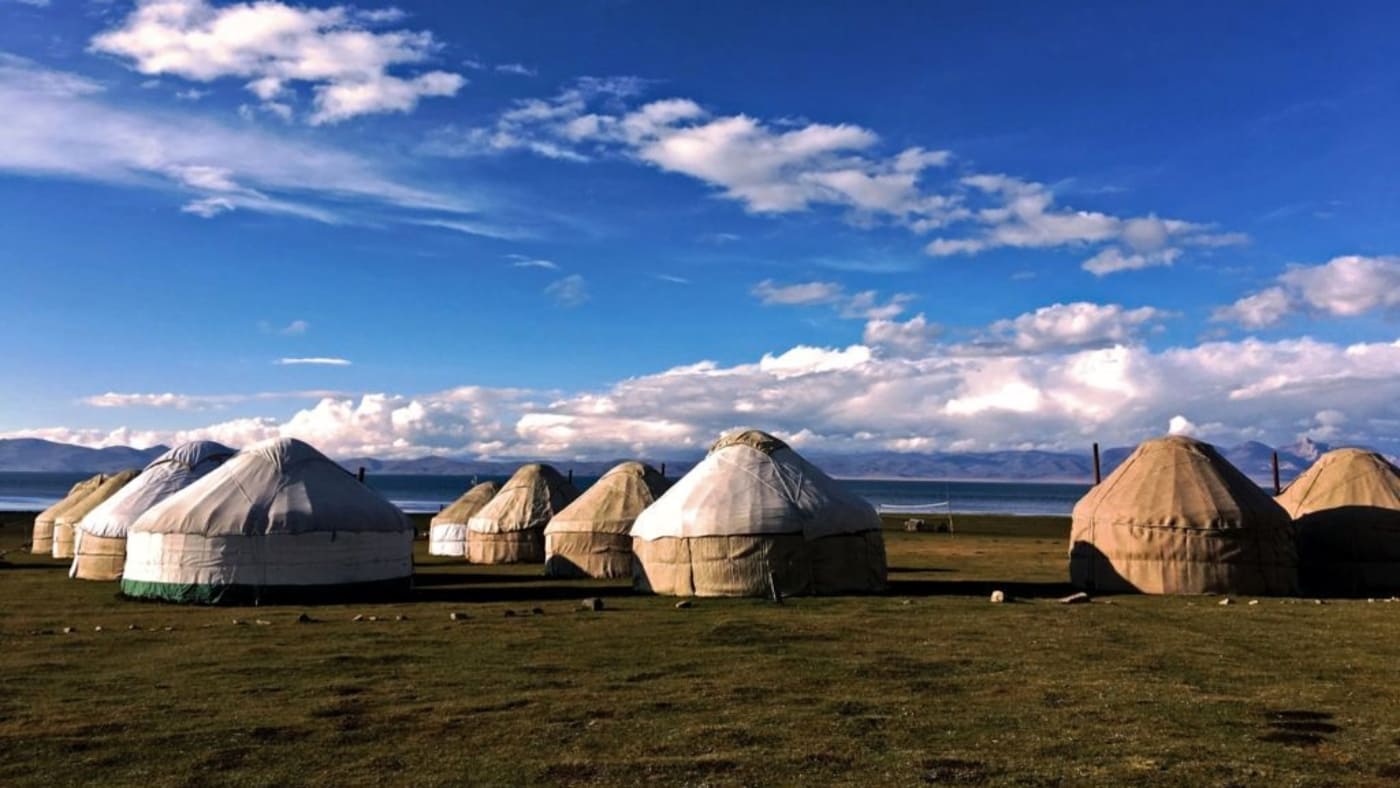 Traditional yurts dot the Kyrgyz landscape under a vast blue sky with B4Experience