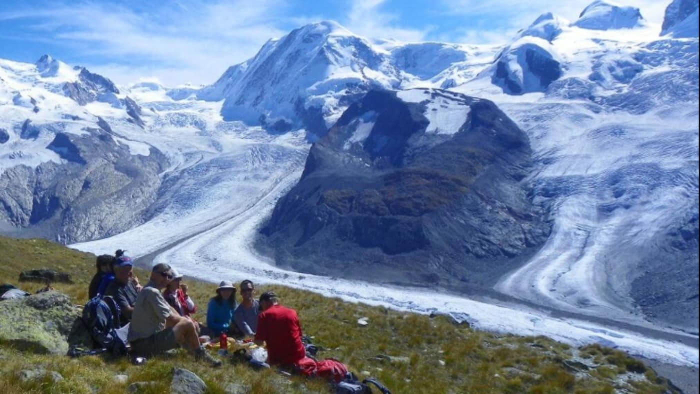 Group of hikers resting on a grassy slopes in the Alps with B4Experience