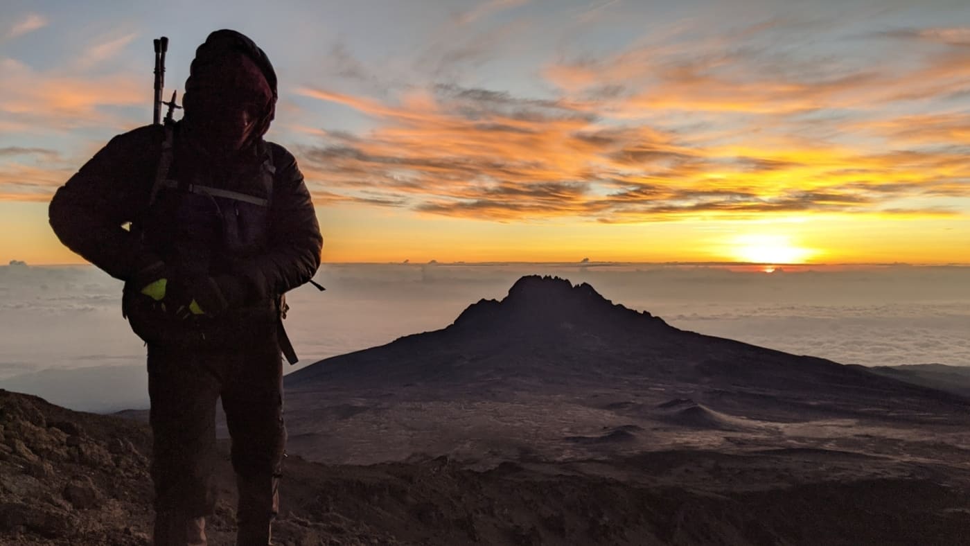 Silhouetted climber at sunrise on Kilimanjaro's summit with B4Experience