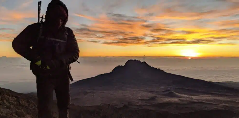 Silhouette of a climber at sunrise on Kilimanjaro's summit with B4Experience