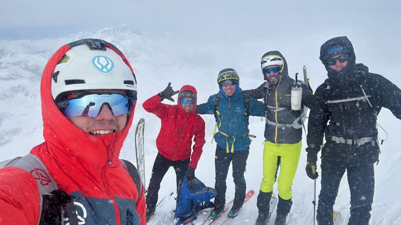 Group of skies in winter gear posing together in the pick of the mountain with B4Experience