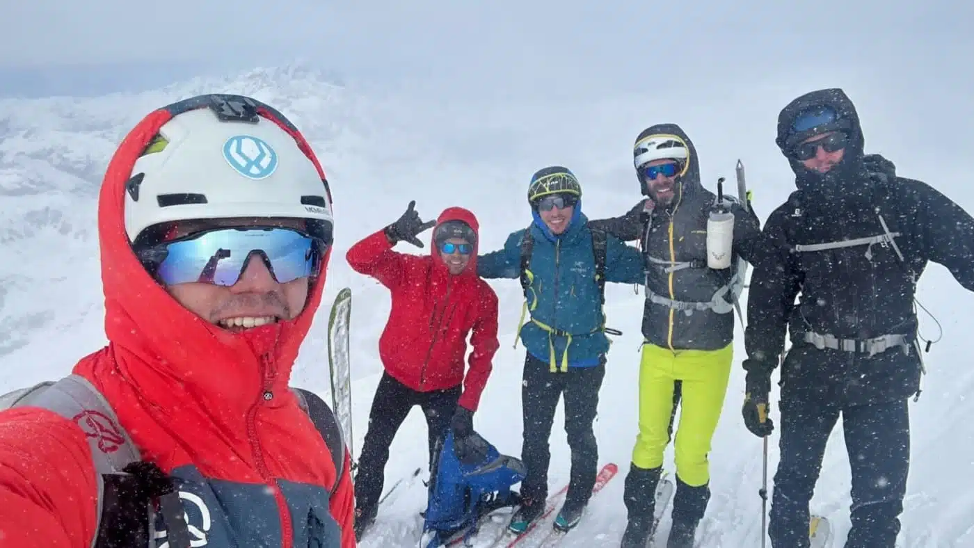 Group of skies in winter gear posing together in the pick of the mountain with B4Experience