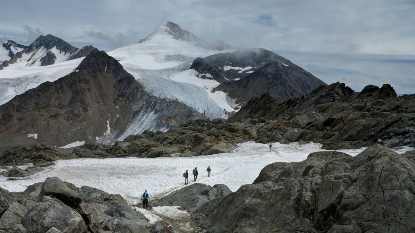 Group of trekkers navigating a rugged glacial landscape in the Alps with B4Experience