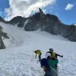 Climbers ascending a snowy mountain with ice axes - B4Experience