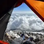 View from inside a tent on a mountain looking out at clouds below- B4Experience