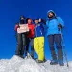 Climbers at Mount Ararat summit with a sign under a clear blue sky - B4Experience