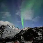A mesmerizing aurora borealis illuminating the night sky over snow-capped mountains - B4Experience