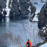 Adventurer in red by a snowy canyon and lake - B4Experience