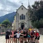 Group of people posing in front of a historic church with mountains int he background - B4Experience