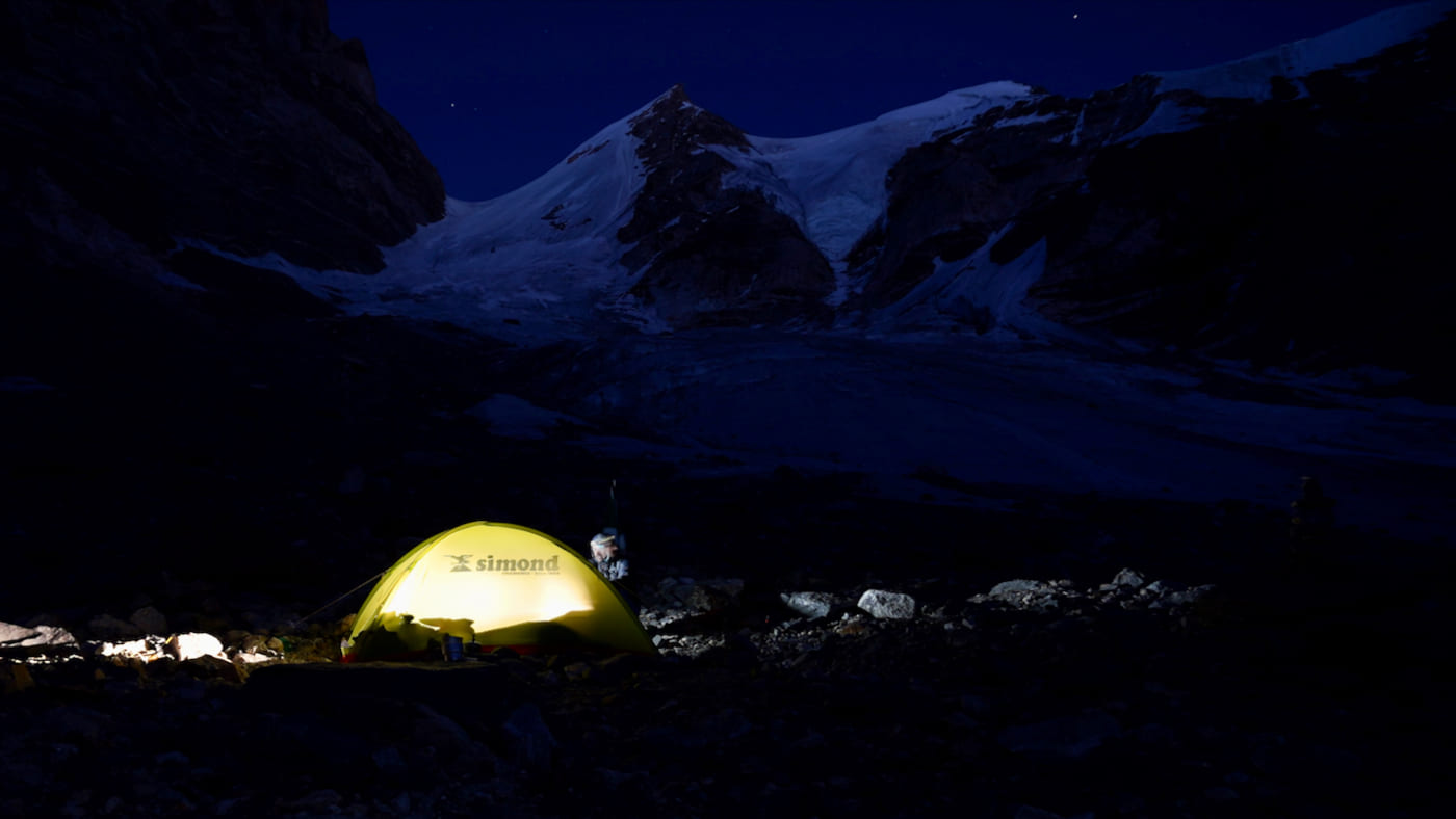 A glowing tent under the starry sky at the base of Laila Peak - B4Experience